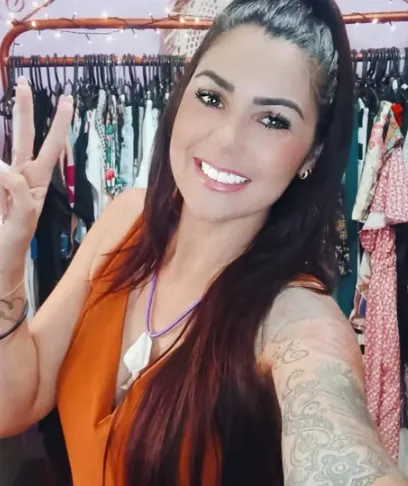 Sarah sorrindo e fazendo o sinal de paz dentro do Trappo Hippie Brechó
